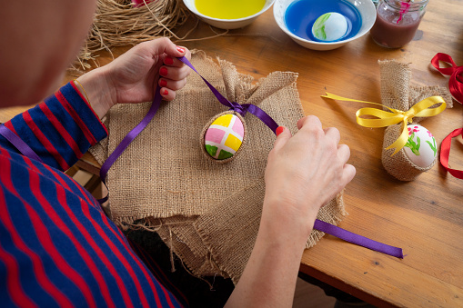 Woman making easter bunny egg, easter decoration on table