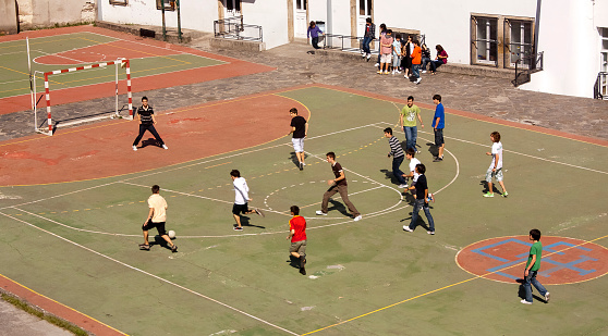 Lugo,Spain - may 21, 2010: group of teenagers , playing football in school yard seen from public pedestrian walkway