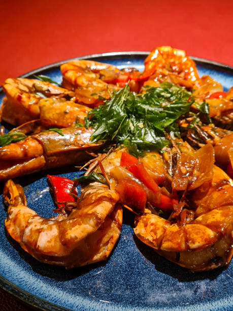istock Pan Fried Tiger Prawn with Basil: Lavish Chinese Cuisine served on a Red Leather Table 1472944882