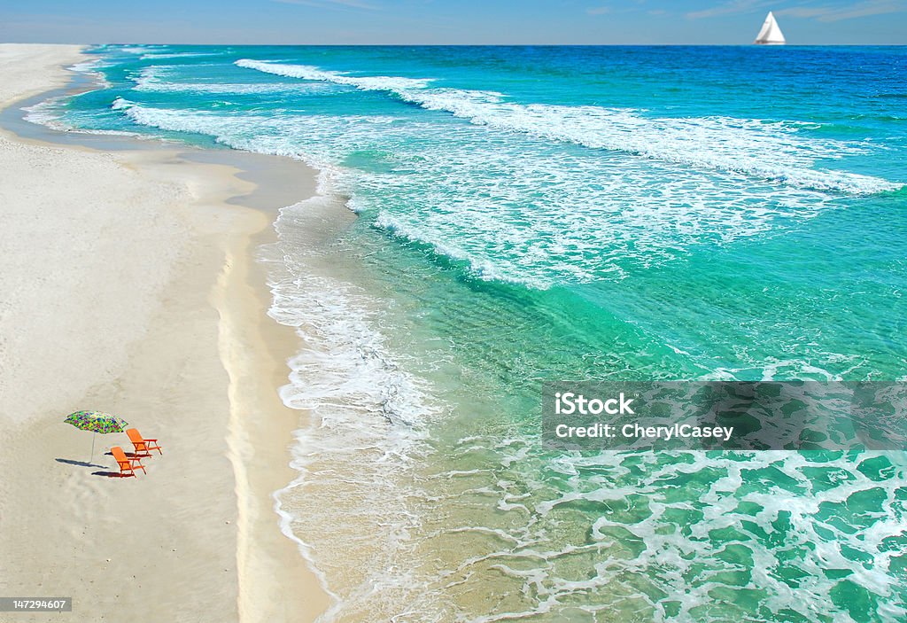 Beach chairs and umbrella Empty beach chairs on deserted beach with sailboat in distance Florida - US State Stock Photo