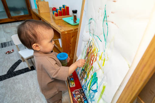 Toddler painting on a paper canvas in montessori kindergarten