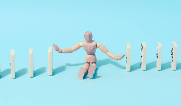 istock A wooden puppet toy holds back a falling domino on a blue background, representing the concept of a strong personality 1472957432