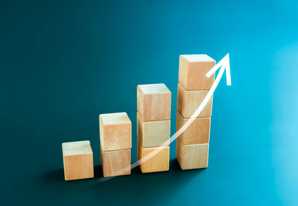 istock White rising up arrow draw on wooden cube blocks bar graph chart steps on blue background, minimal style. Purchase trend increase, income, inflation, business marketing growth concepts. 1472958223