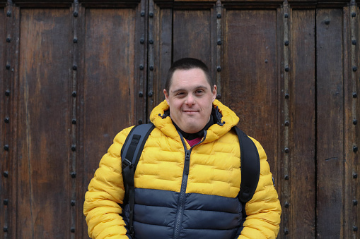 A young man with Down's syndrome stands outside a wooden door in Oxford, England