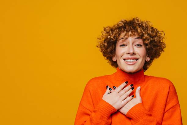 istock Middle-aged woman smiling and holding hands on her chest while standing isolated 1472963748