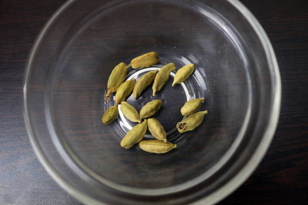 Green cardamom or cardamon or cardamum or green elaichi in glass bowl isolated on white background