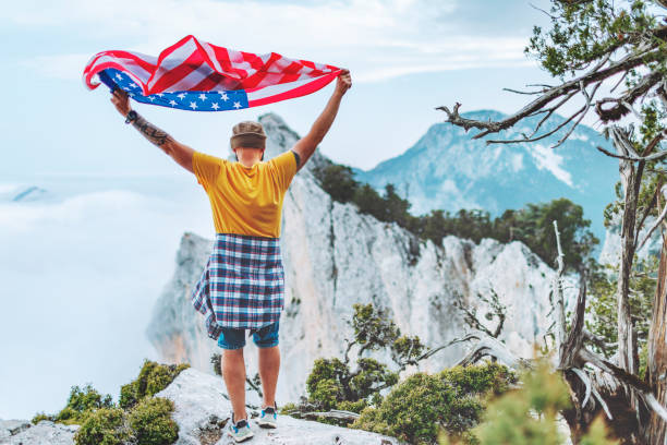 istock Man with American flag on the top on mountain 1472965937