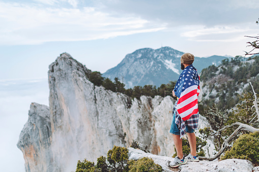 Man with American flag on the top on mountain