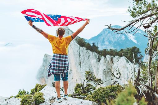 Man with American flag on the top on mountain