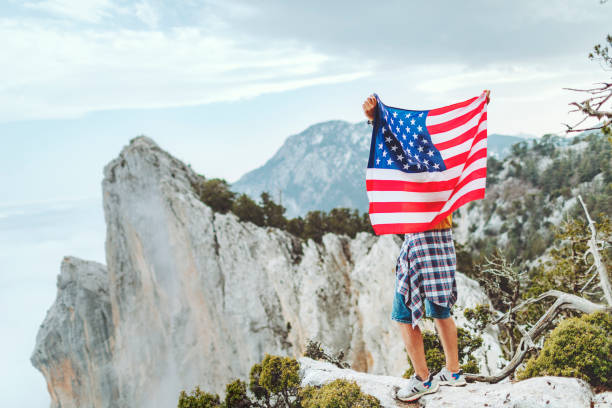 istock Man with American flag on the top on mountain 1472966133