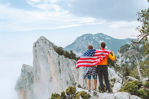 Friends with American flag on the top on mountain