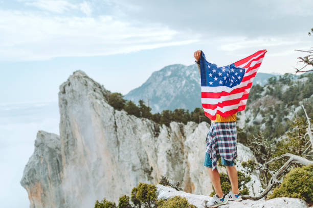 istock Man with American flag on the top on mountain 1472966304