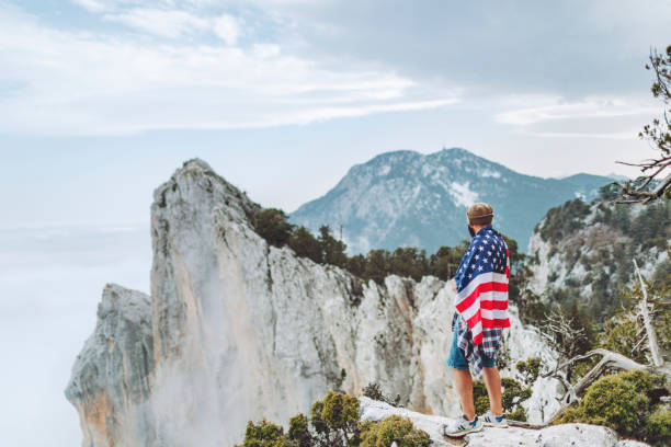 istock Man with American flag on the top on mountain 1472966327