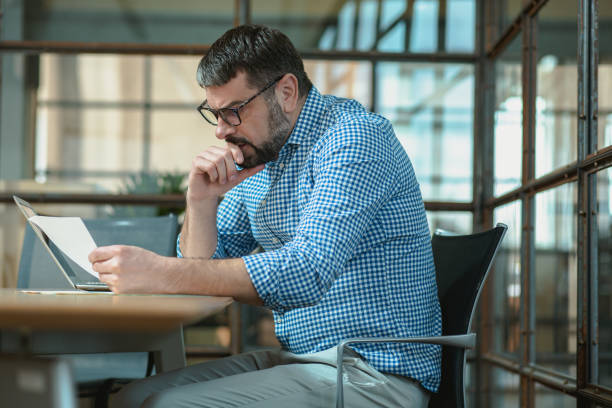 istock Man carefully checking information in project report in the office 1472966633