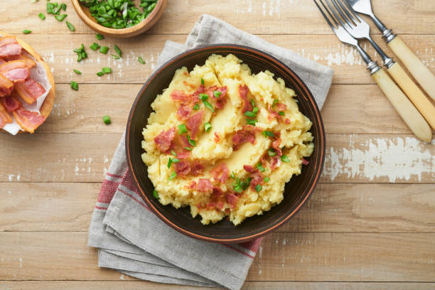 istock Mashed potatoes. Bacon mashed potatoes with green onion, pepper and cheddar cheese in bowl on old wooden backgrounds. Delicious creamy mashed potatoes. Top view. 1472967981