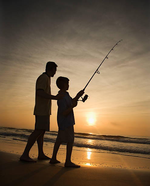ojciec i syn na ryby na plaży - fishing rod fishing fishing reel casting zdjęcia i obrazy z banku zdjęć