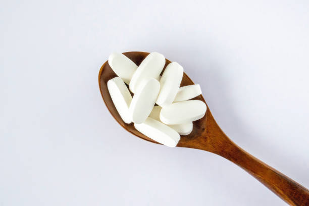 istock L glutamine white oval tabletsin a wooden spoon on a white background, top view. 1472970798