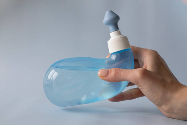 neti topf. ayurvedische medizinische werkzeuge, um ihre nase zu hause mit wasser und salz zu reinigen. blaue schüssel wasser in der hand einer frau - neti stock-fotos und bilder