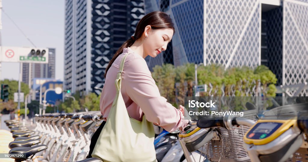 woman rent a bike commute asian businesswoman using smart watch to rent and ride a bike commuting in the city Asia Stock Photo