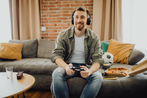 istock Joyful young man playing a video game 1472972238