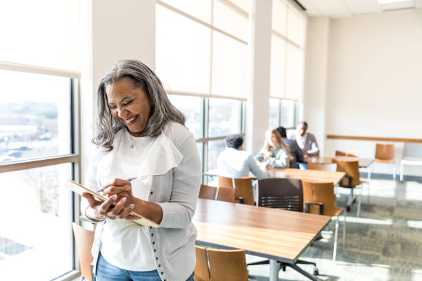 istock Supervisor smiles and makes notes on her clipboard as she stands in the conference room 1472972321