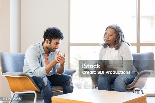 istock Young adult male gestures while speaking with his mental health therapist 1472972348