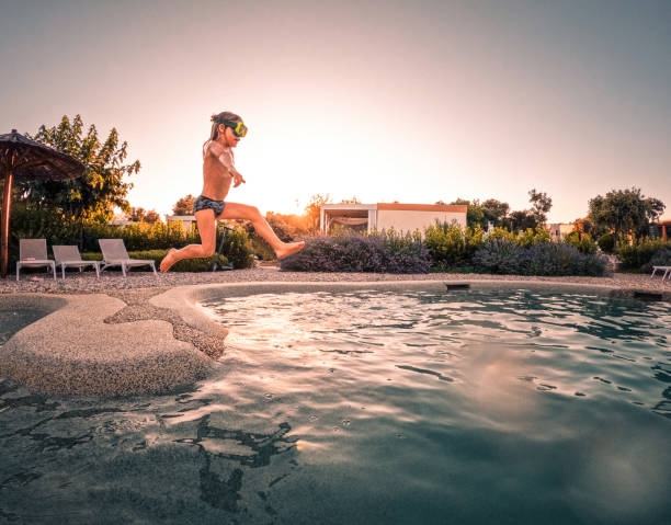 istock Caucasian Small Boy Jumping High into Big Swimming Pool 1472972517