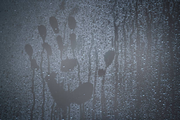 Handprint on a blurry window glass with droplets of water