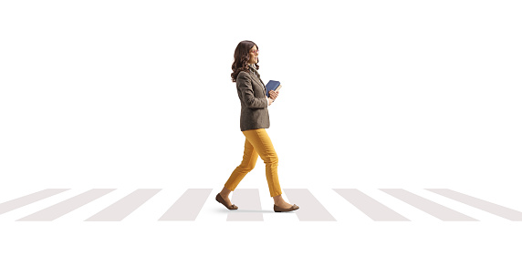 Young woman carrying books and crossing street isolated on white background