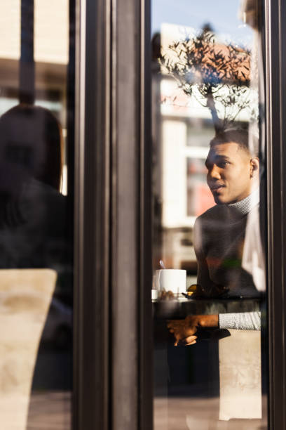 istock Friends in a restaurant smiling and having a conversation. View from outside with window reflections.. 1472973490
