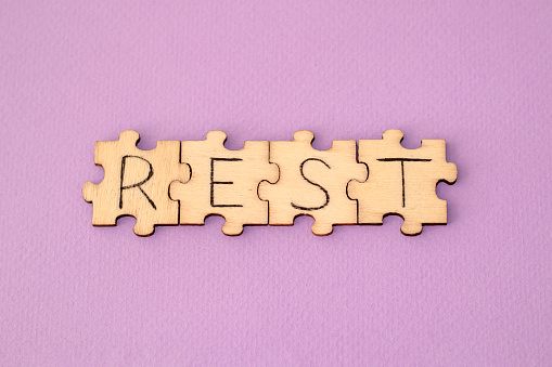Learning Rest. The hand lettering on the wooden puzzles is on a purple background