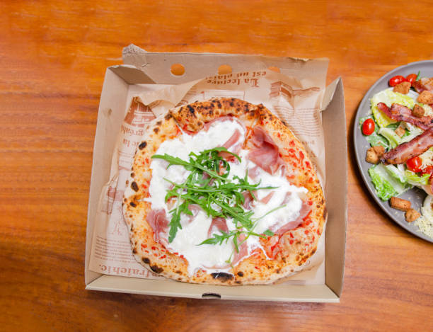 istock A baker making bread in the kitchenPizza with parma ham Italian style in a paper box 1472974780