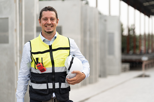 Portrait caucasian engineer man holding hardhat at precast site work