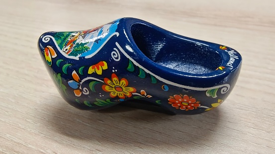 Amsterdam, Holland, 12.12.2022: Traditional souvenir clogs for sale, a must from the Netherlands. Colourful wooden clogs painted with regional motifs. Travel destination background of Dutch tradition.