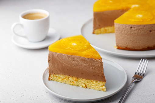 Шоколадно-апельсиновый муссовый торт с бисквитной основой, желе и кружочками апельсина. Кусок домашнего чизкейка и чашка кофе. Традиционны