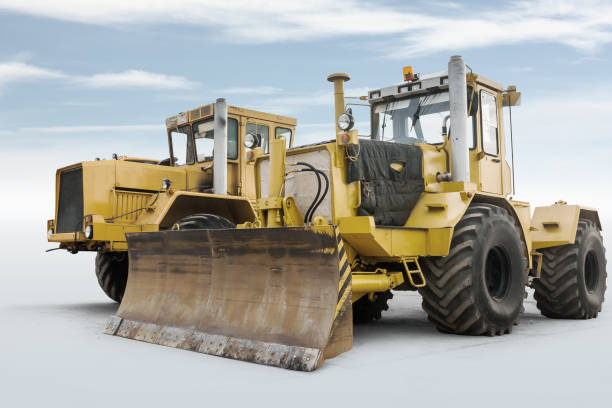 istock Two yellow heavy wheeled tractors isolated on bright background with sky 1472986822