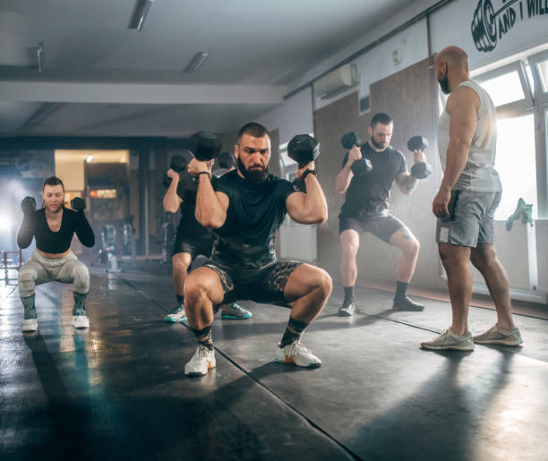 istock Athletic people having cross training with dumbells in a gym 1472988352