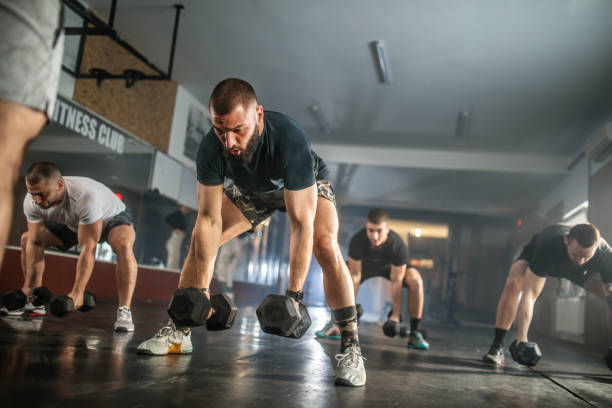 istock Athletic people having cross training with dumbells in a gym 1472988881