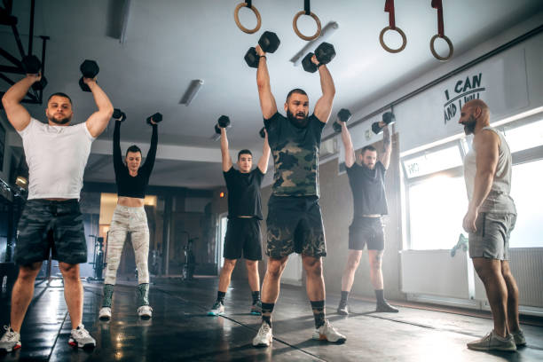 istock Athletic people having cross training with dumbells in a gym 1472988960