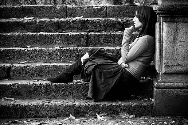 Young thoughtful woman sitting in stone stairs.