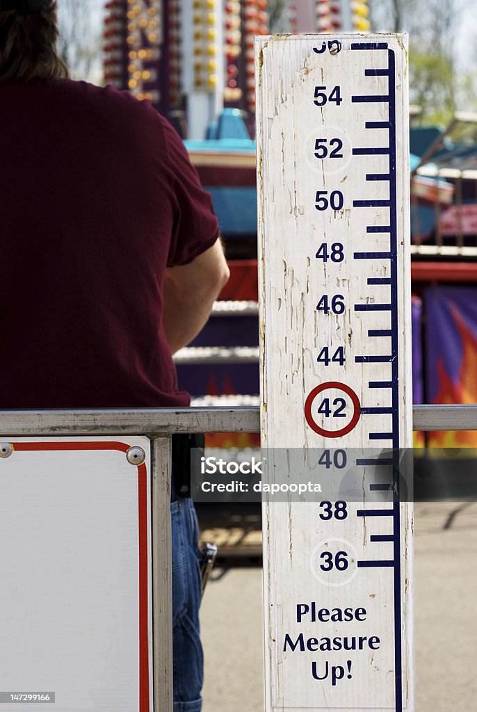 Please Measure Up Sign at Carnival A height measuring stick is displayed in front of a ride for young children to measure up to check their height. Human Height Stock Photo