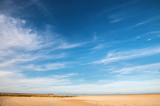 A blue sky with high cirrus clouds meets the sand flats around San Ignacio Lagoon in the central part of the Baja Mexico.  The shot is below Reserva de la Biosfera El Vizcaino. nature preserve.  There is a lot of copy space in this wide angle shot.