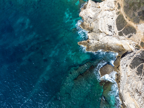 drone shot of woman lying on the rocks of Cape Kamenjak, a protected natural area on the southern tip of the Istrian peninsula in Croatia, Europe