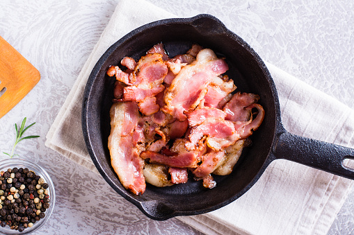 Fried bacon in a pan ready for dinner on the table. Top view. Closeup