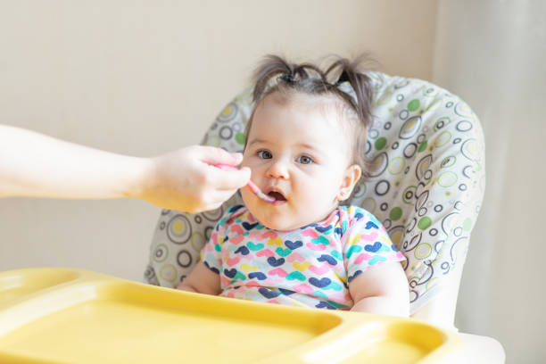 istock baby eats mashed potatoes, mom feeds baby from a spoon, baby food concept 1472999241