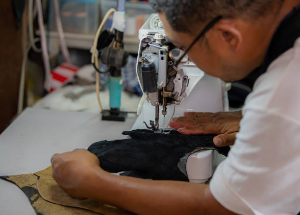 istock Working process of leather craftsman. Tanner or skinner sews leather on a special sewing machine, close up.worker sewing on the sewing machine 1472999365