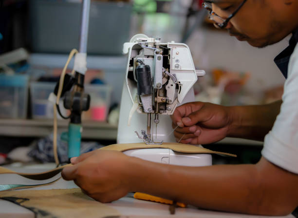 istock Working process of leather craftsman. Tanner or skinner sews leather on a special sewing machine, close up.worker sewing on the sewing machine 1472999390