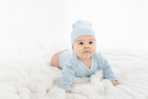 a baby in blue clothes is lying on his stomach on a white rug