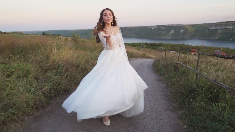 A bride in a wedding dress runs off into the distance on a dirt road slow-motion