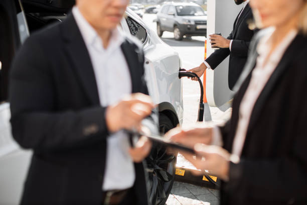 istock Business people using gadgets and charging electric car 1473003909